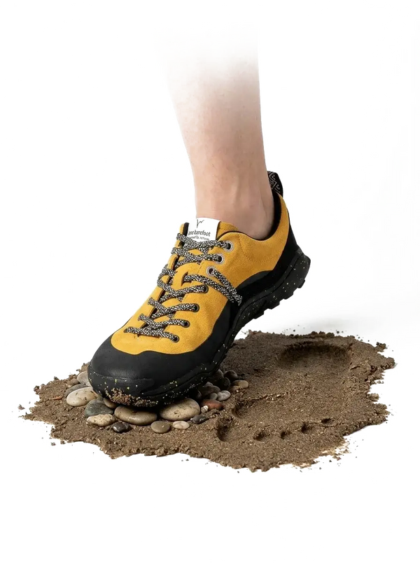 LONO WILD shoe stepping onto sand and pebbles, thin sole bending over the stones
